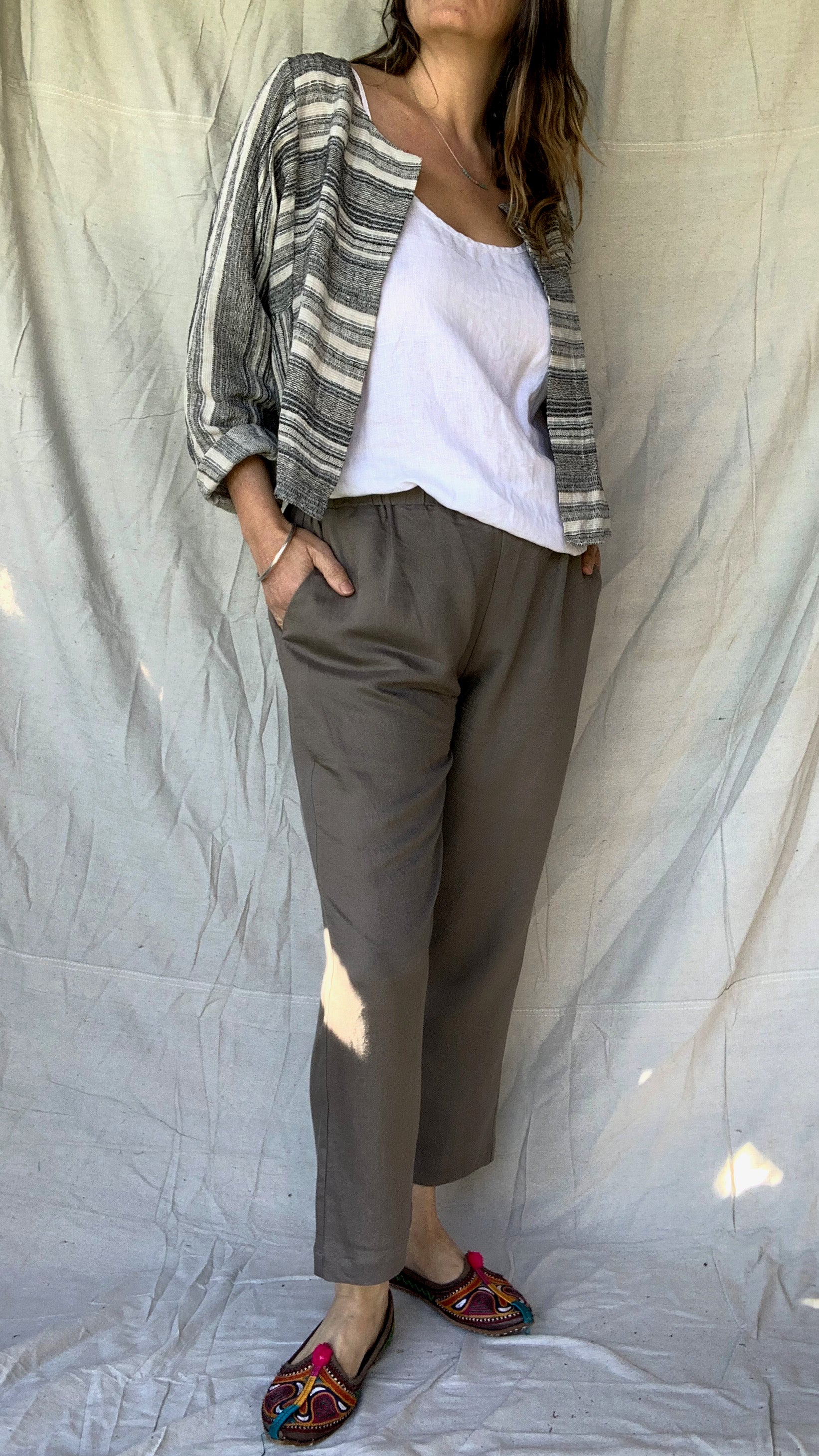 Casual linen pant with a slight tapered leg, elasticated waist and pockets worn with a white linen top and a soft linen jacket in black and natural stripe.